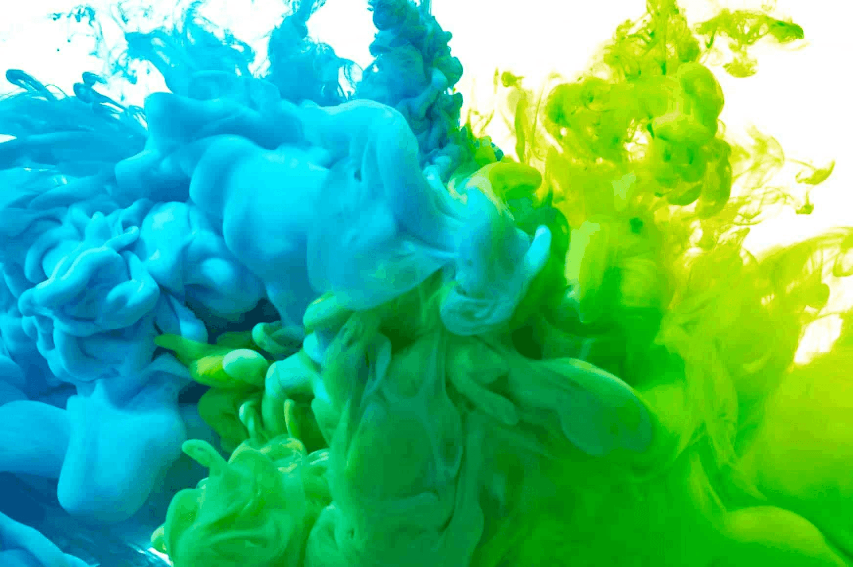 Vibrant blue and green ink swirling in water