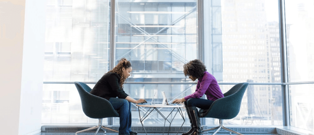 women mentor and mentee sat in front of each other while working