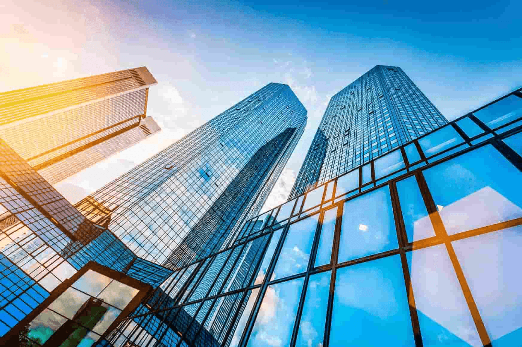 Low angle view of modern skyscrapers with glass facades under a clear blue sky.