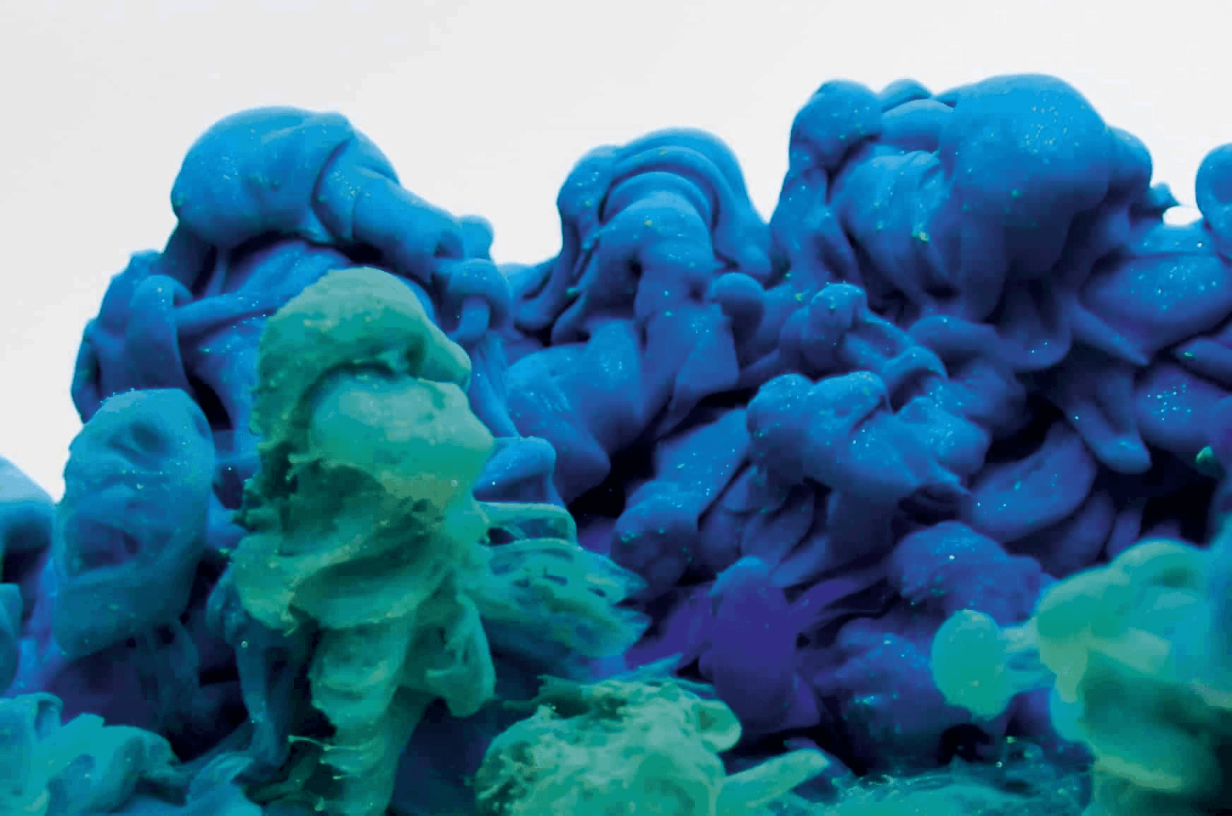 A close-up view of vibrant blue and turquoise slime or putty with a gooey and amorphous texture.