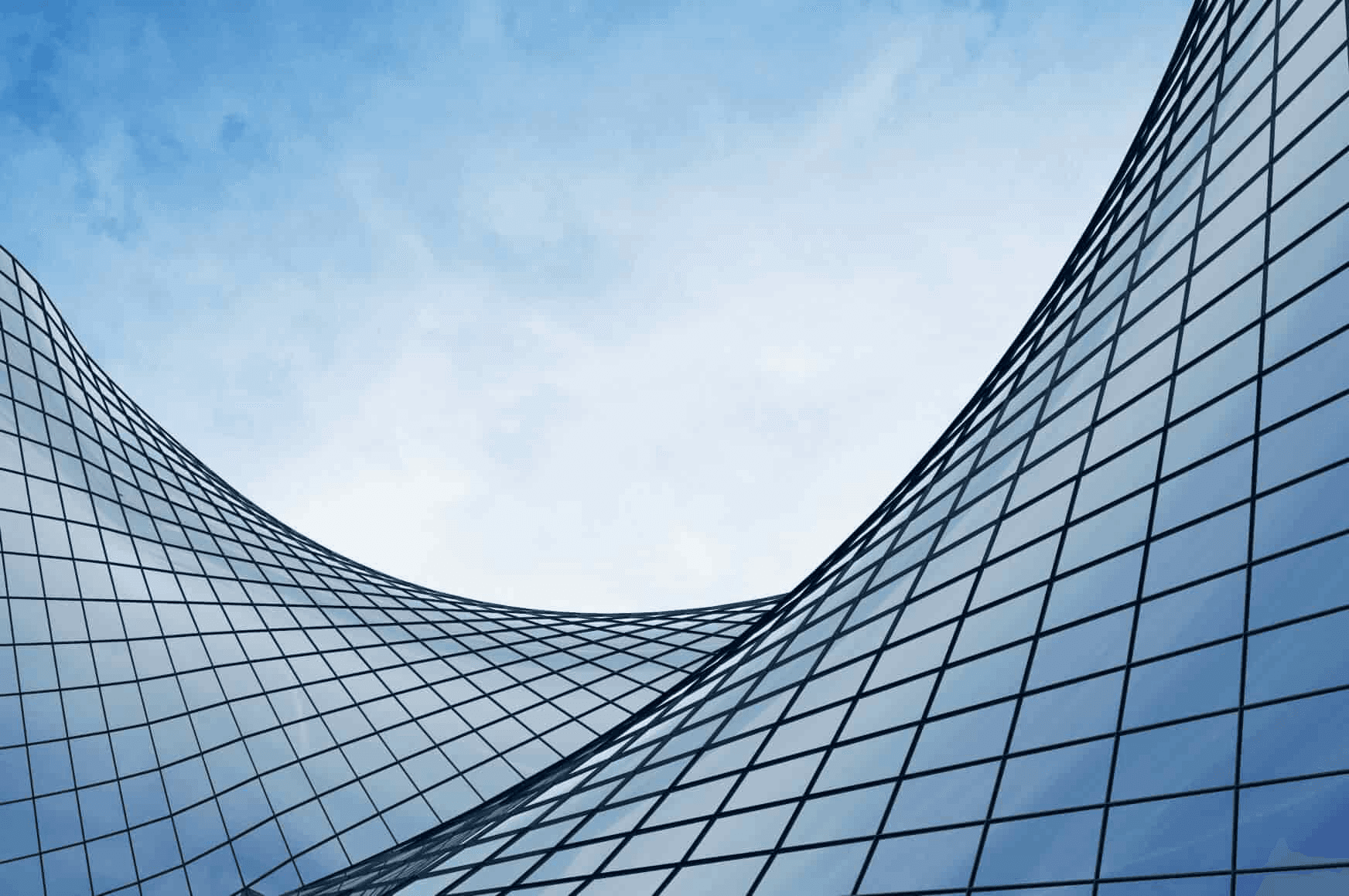 Abstract view of curved glass buildings against a clear sky.