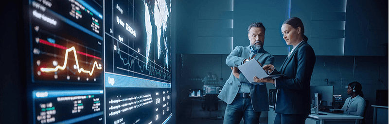 Two business professionals are discussing data analysis in a modern office environment.
