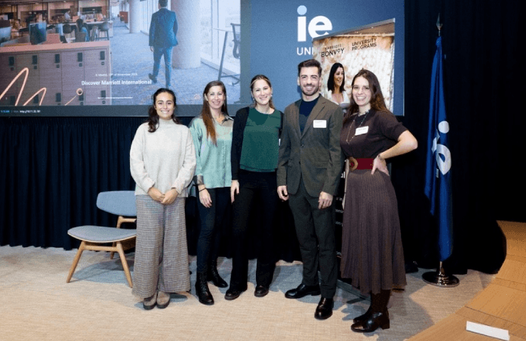 Five people standing together in a conference room with a IE University banner in the background.
