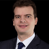 Portrait of a smiling businessman in a dark suit and blue tie.