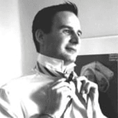 A black and white photo of a man in a tie looking at an X-ray.