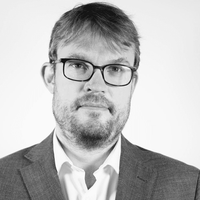 Black and white portrait of a middle-aged man wearing glasses, a suit, and a white shirt.