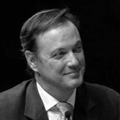 Black and white photo of a smiling man in a suit.