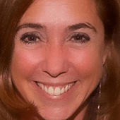 Close-up portrait of a smiling woman with brown hair.