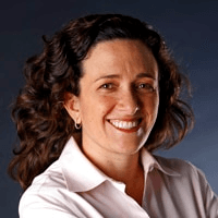 A portrait of a smiling woman with curly hair wearing a white shirt against a blue background.