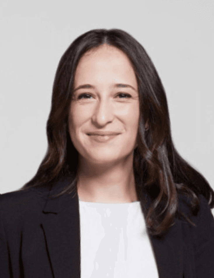 Portrait of a smiling woman wearing a black blazer and white top.