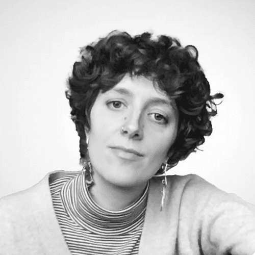 Black and white portrait of a woman with curly hair wearing a striped turtleneck and earrings, looking slightly to the side.