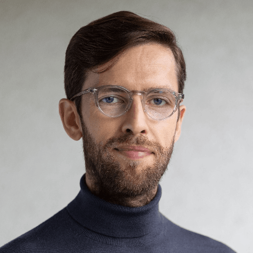 Portrait of a man with glasses wearing a turtleneck sweater.