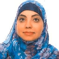 A portrait of a woman wearing a blue patterned hijab looking directly at the camera.