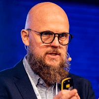 A man with a beard and glasses is giving a presentation holding a microphone.