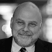 Black and white photo of a smiling bald man with a beard, wearing a suit and tie.