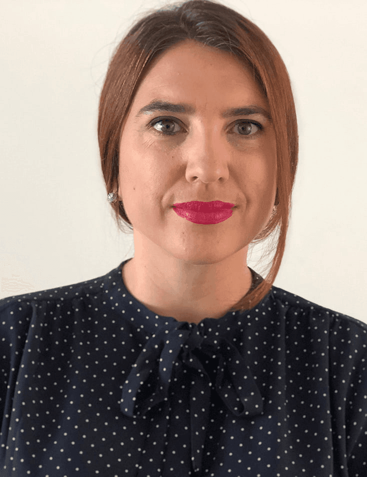 A woman with pink lipstick wearing a navy blue polka dot blouse.